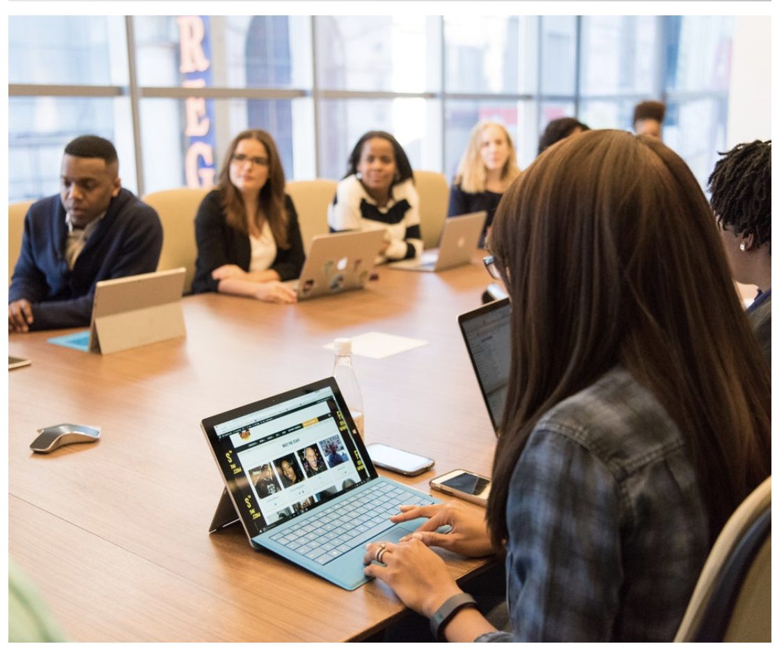 A team meeting around a conference table with laptops